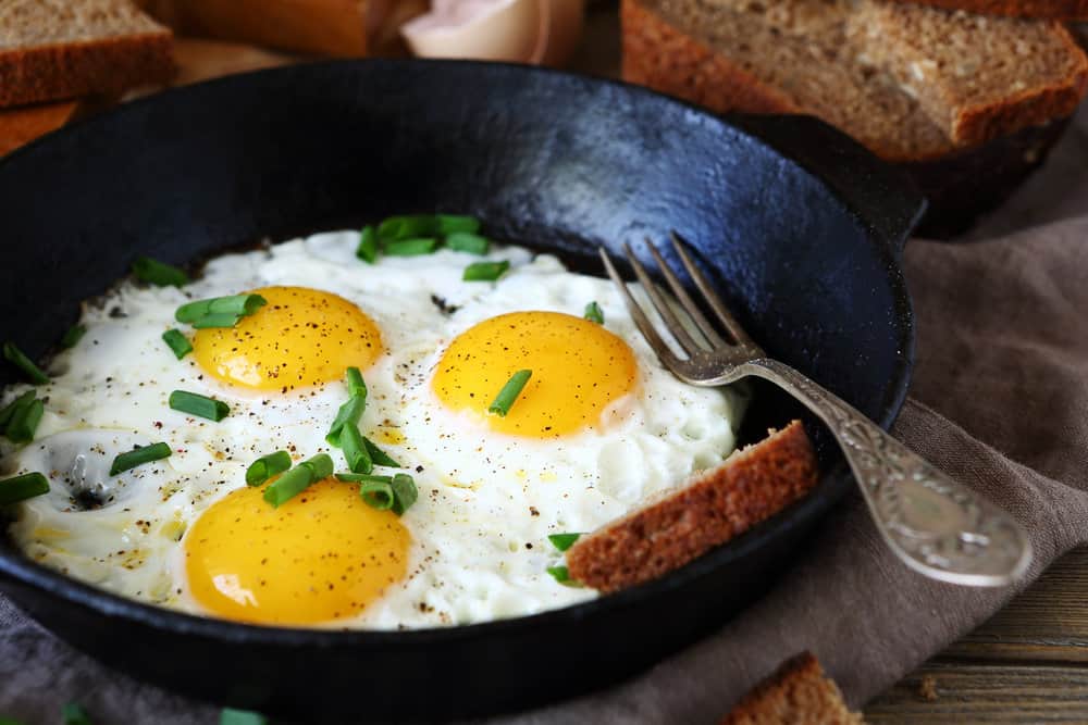 Three perfectly cooked, sunny-side up eggs with fully set whites and runny yolks, seasoned with of salt and pepper.