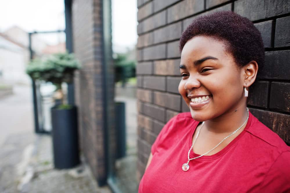 A black girl with a round face wearing a short natural haircut in dyed TWA style after big chopping her long hair.