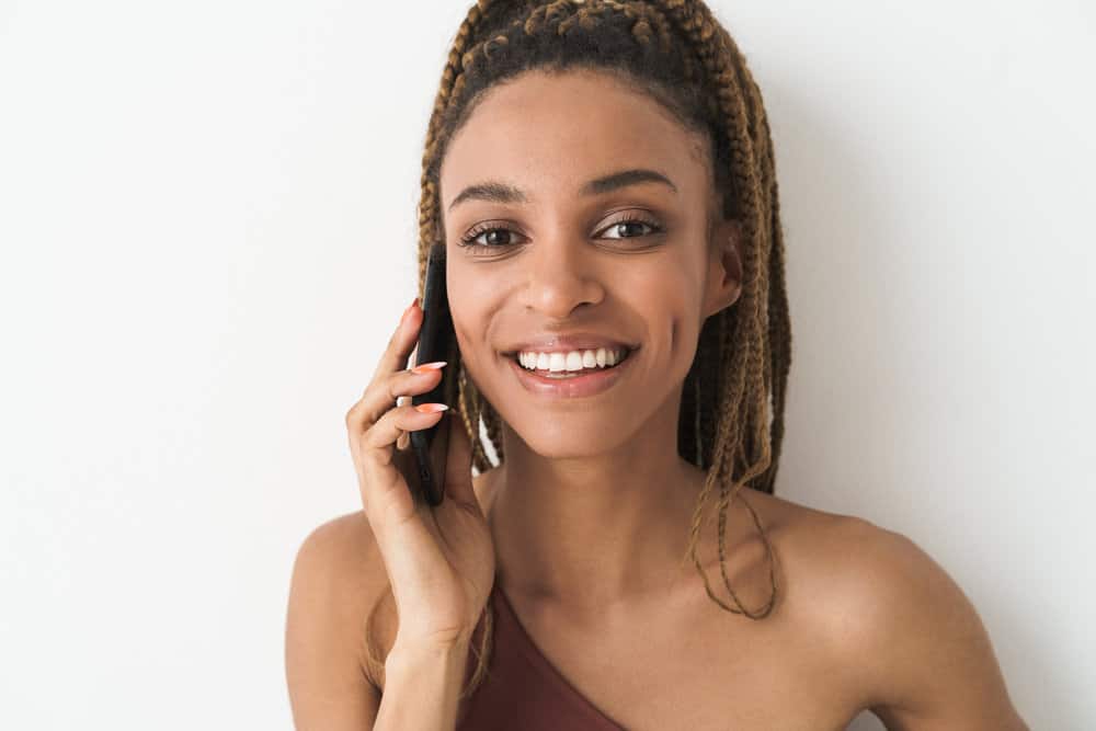 A light-skinned black girl's invisible crochet braids have a perfect top knot bun showing off her natural beauty.