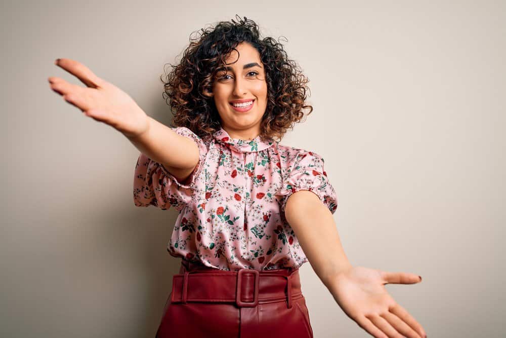 An Arab woman's curly hair texture and rose gold skin tone are a perfect match for pretty caramel highlights.