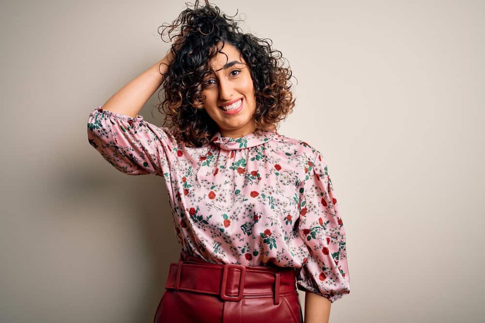 A young woman with black hair and a light brown hair color provides face-framing highlights for her brown skin color.