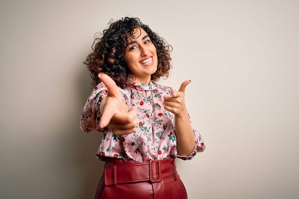 A beautiful female with natural curls has light brown highlights complimenting her jet-black hair color.