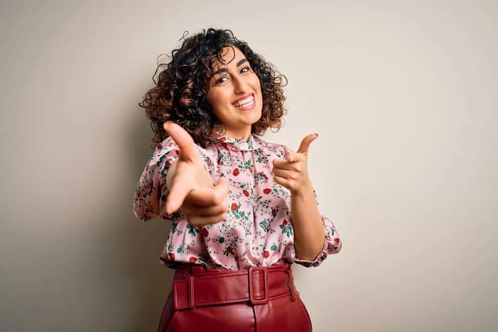 11 Best Hair Color Ideas, Shades, Trends, and Inspo for Women 2 A beautiful female with natural curls has light brown highlights complimenting her jet-black hair color.