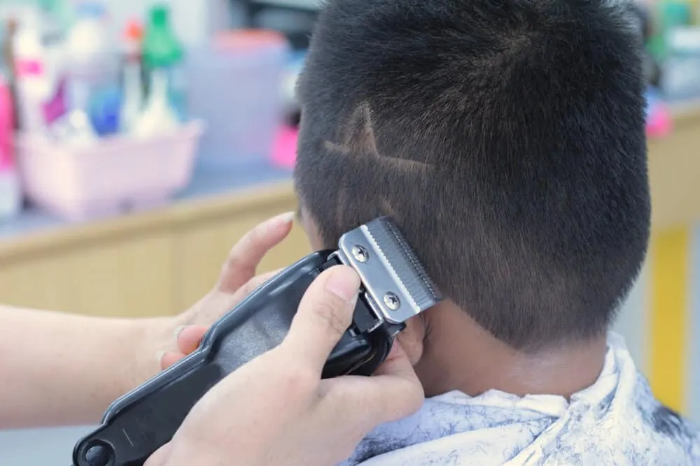 Haircut Lines: Barber Line Designs for Black and White Guys 1 A little boy with straight hair is getting a double-line haircut with sharp edges on his naturally short hair.