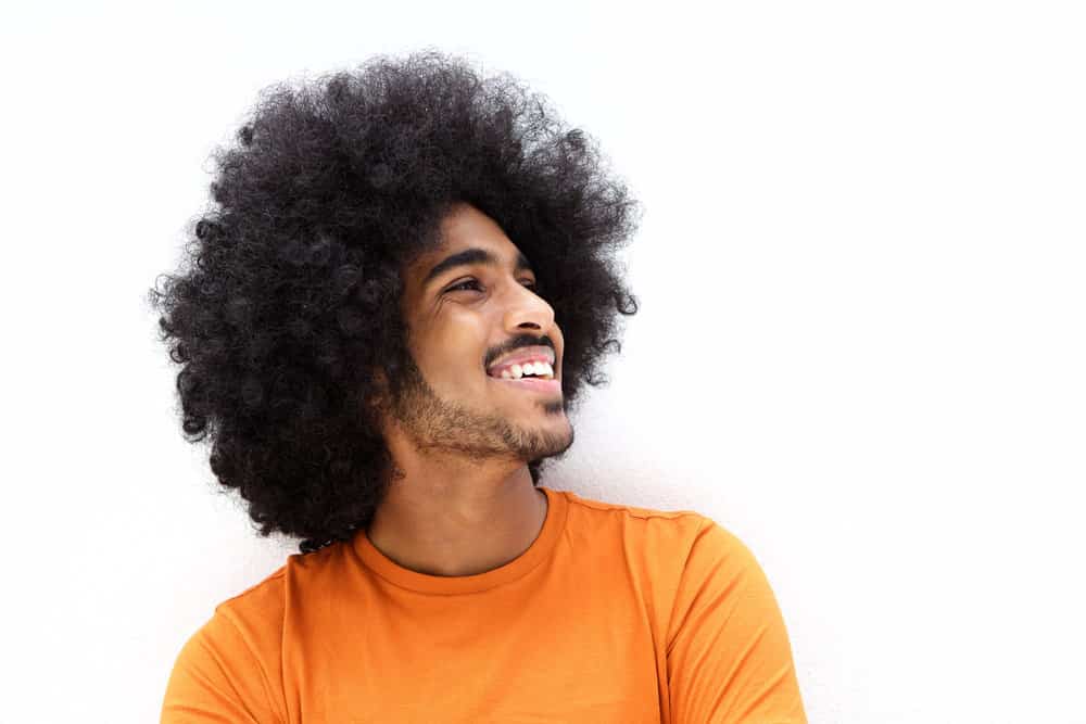 A proud African American male with thick, hydrated hair wearing a wash-and-go style showing off his natural texture.