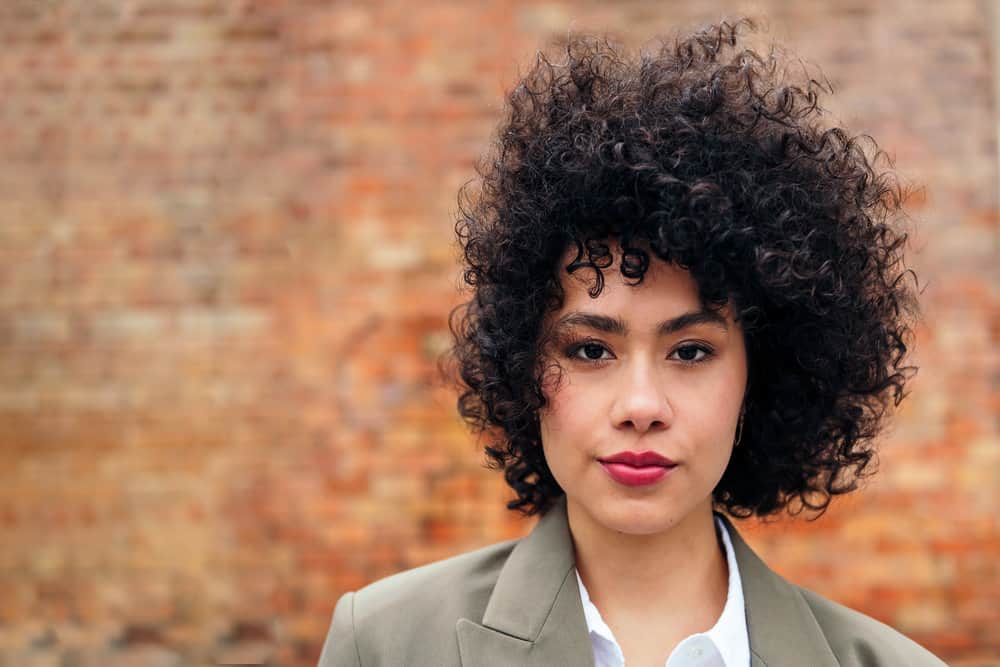 A black girl with curly, wavy hair strands after styling her bouncy curls with a blow dryer for wet and dry hair strands.