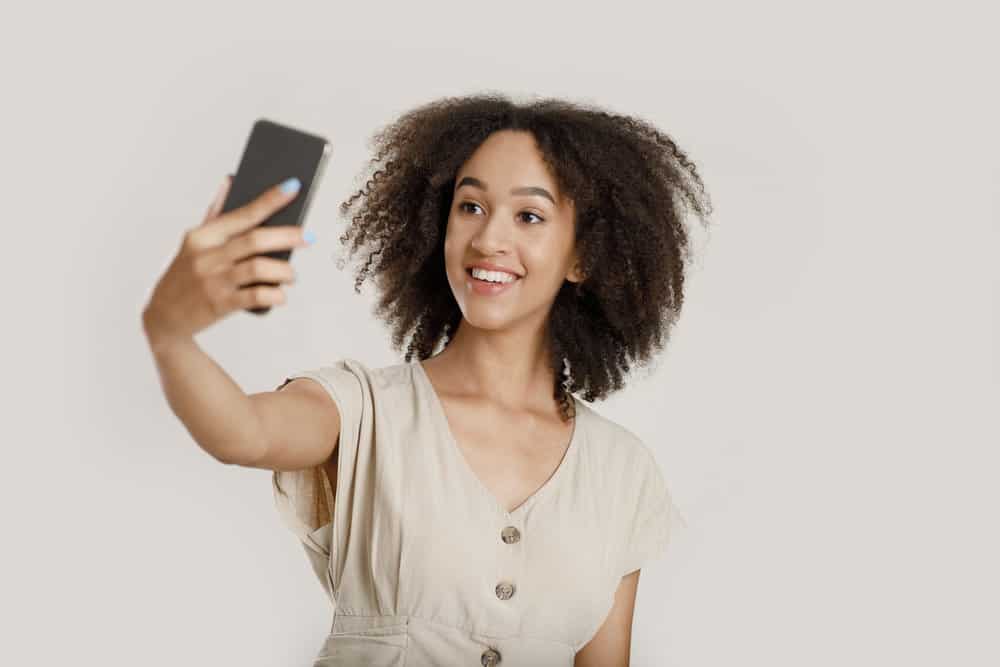 African American taking a selfie of her new bangs with a curly hairdo with a middle part.