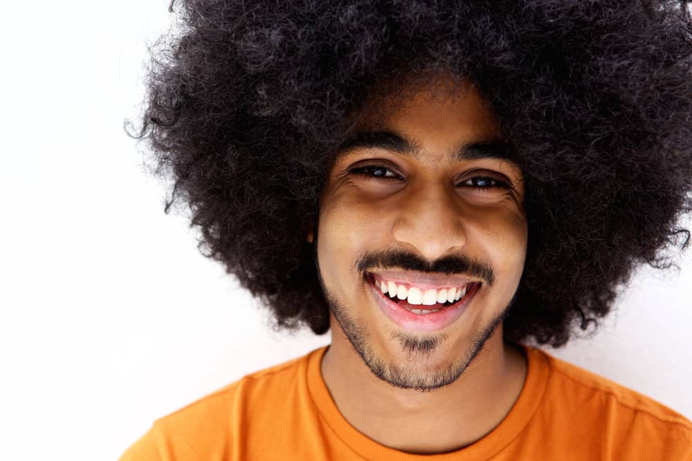 African American male with type 4 black hair uses natural oils and avoids harsh chemicals to encourage hair growth.