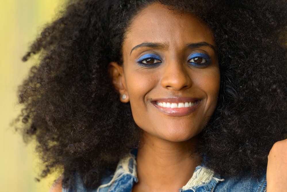 African American female with chemically-treated dark brown damaged hair strands from tight hairstyles.