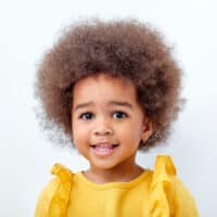 A beautiful African American child with short curly hair in a big afro style showing off her defined curls.