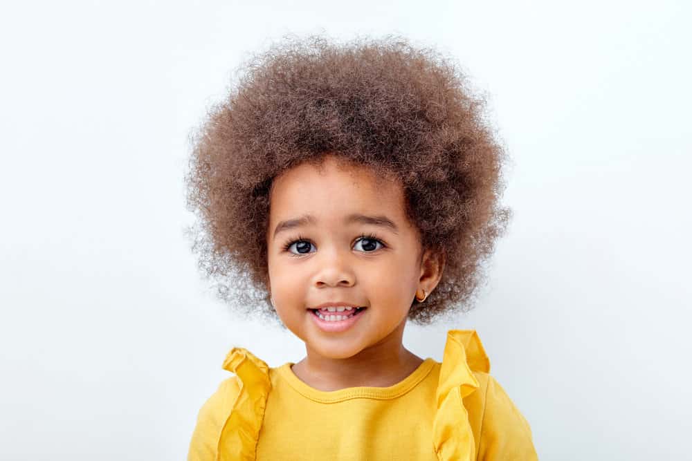 A beautiful African American child with short curly hair in a big afro style showing off her defined curls.