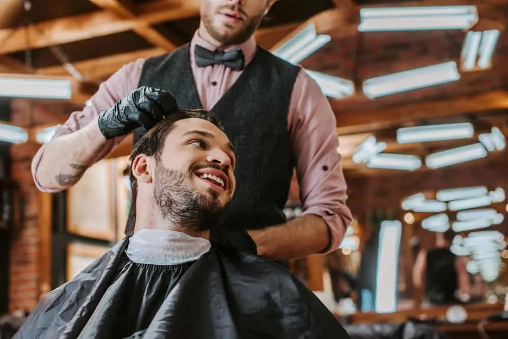 A male at his local barbershop is getting a fresh bald fade Edgar cut (sometimes called a high and tight Edgar).