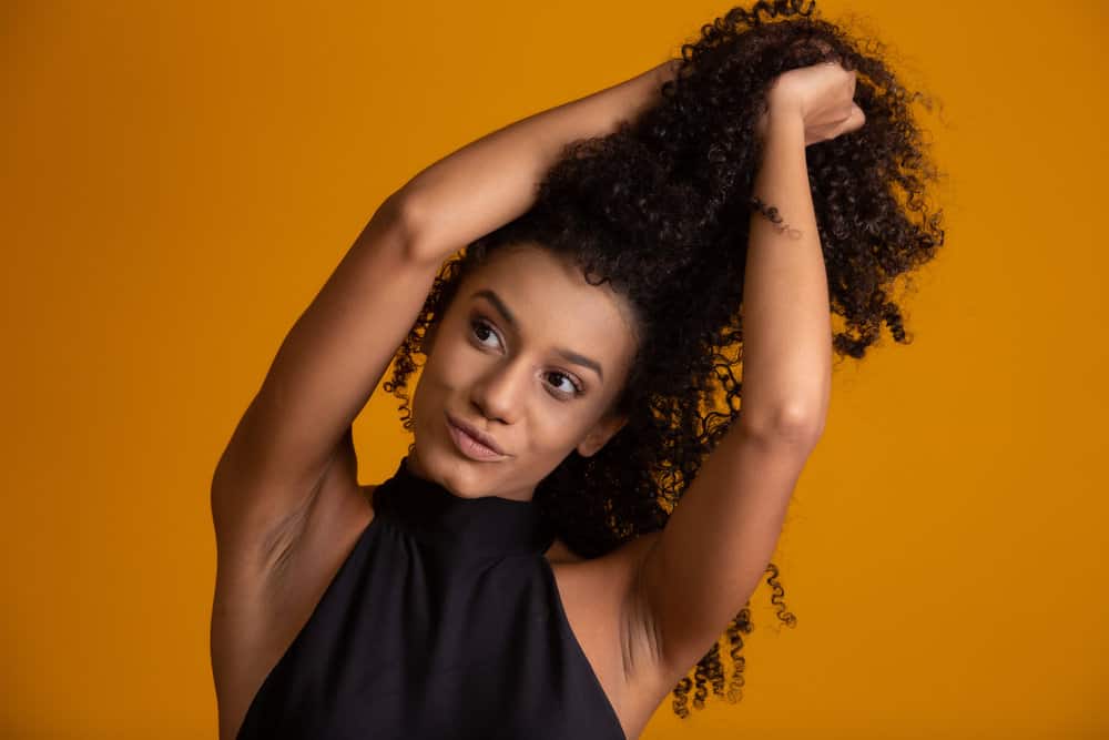 African American female with a chest-length wavy haircut is wearing a style with volume and natural movement.