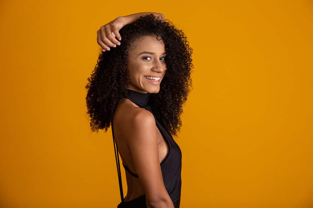A lovely black female with gentle waves, sporting chic curtain bangs with vintage curls, long hair, and a great smile.