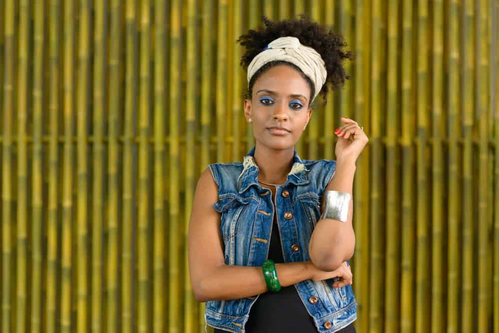 A young African female with frizzy hair manages hair porosity using natural oils like castor oil and coconut oil.