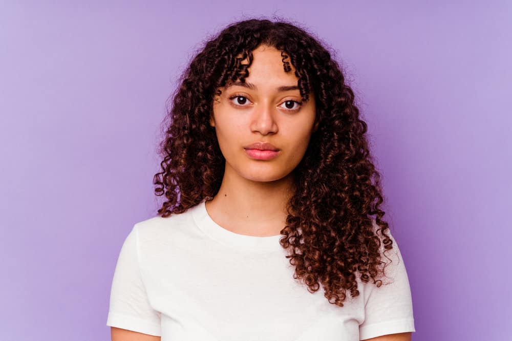 A mixed race female looking directly into the camera wearing red lipstick, eye shadow and a white tank top.