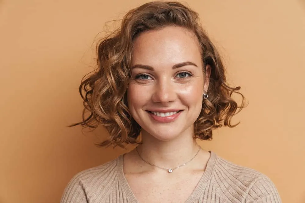 12 Best Medium-Length Haircuts With Layers, Bangs, & More 1 A young white female with medium-length layered hair with beautiful swoopy layers and wispy bangs.