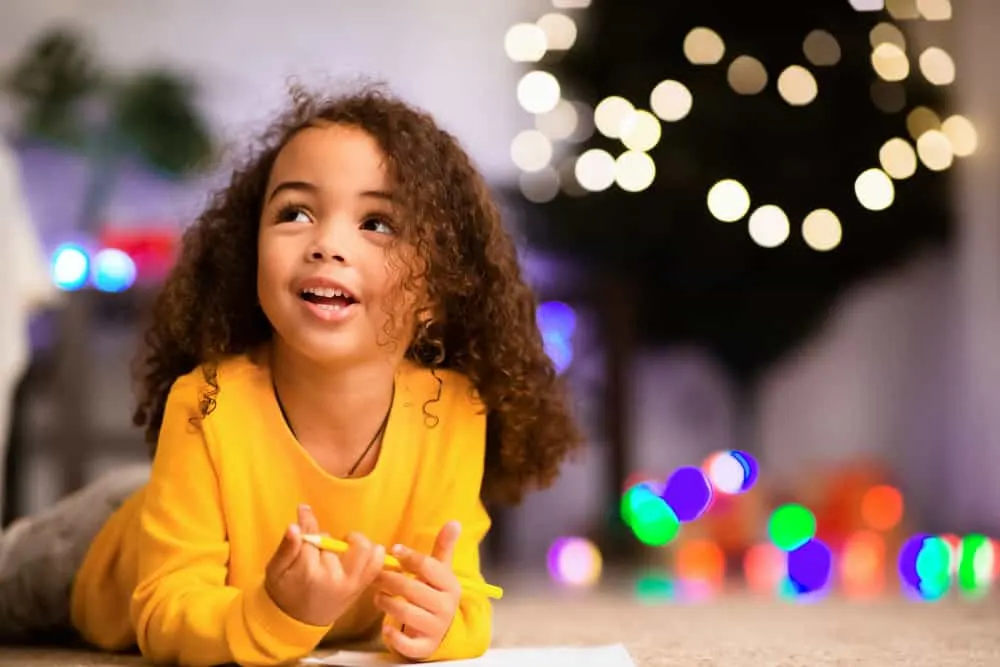 15 Cute and Easy Toddler Girl Hairstyles with DIY Tutorials 16 A mom takes a picture of her daughter's hair as her lovely little girl plays with a pencil and a sheet of paper.
