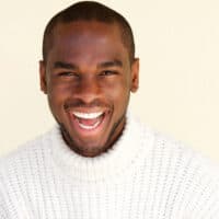 A young African American male with naturally thick hair has an ivy league haircut that's similar to a classic crew cut.