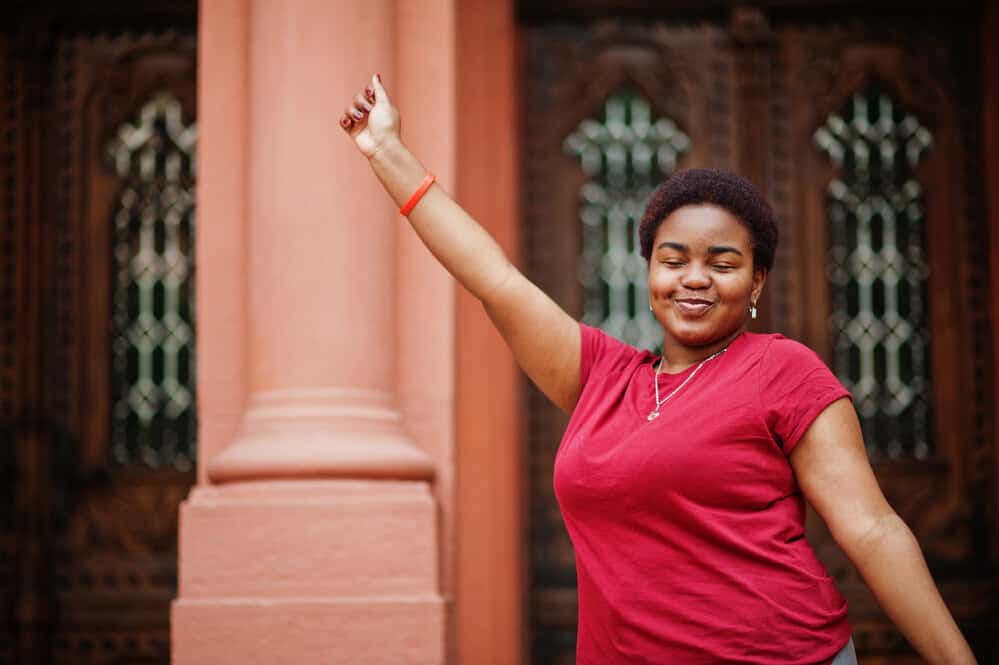 African woman wearing a simple style on her red-dyed 4C natural hair that's been treated with coconut oil.