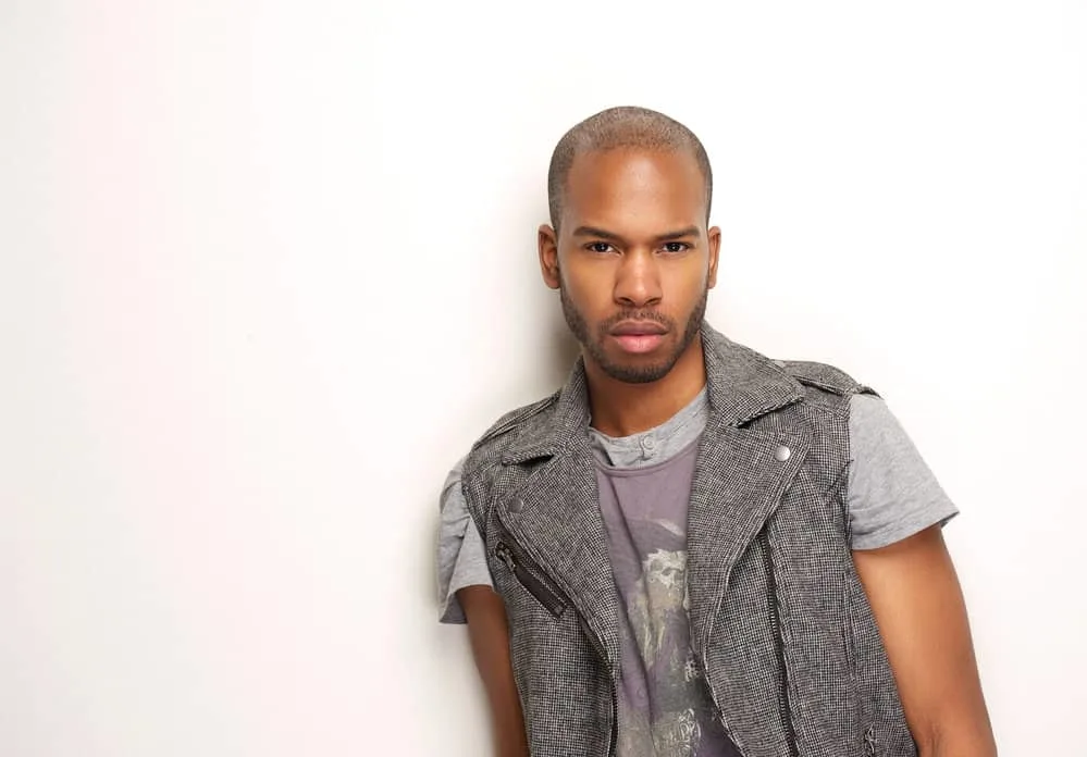 Best Male Haircuts for Receding Hairline and Widow’s Peak 4 A black man with a bold sense of style wearing a high skin fade on his naturally wavy texture.