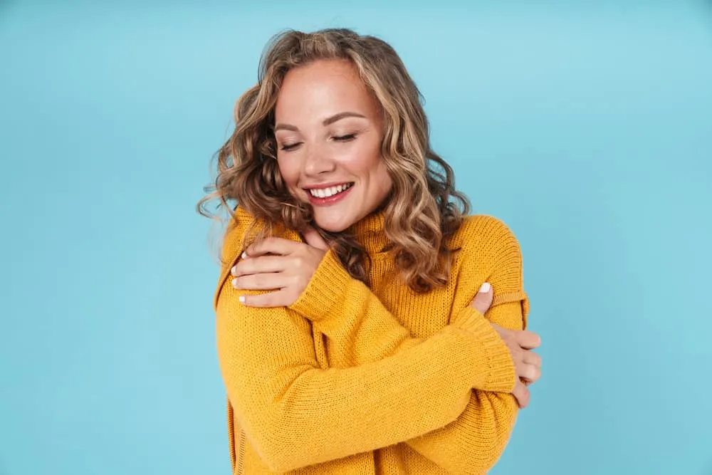 How to Fix Limp Curls: Why Are My Curls Limp and Stringy 4 A Caucasian woman with voluminous curls keeps her hair hydrated with hair creams and water-based styling products.