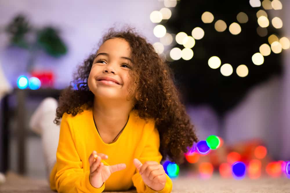 A beautiful African American girl wearing an easy toddler girl hairstyle that's common for kids with curly hair types.