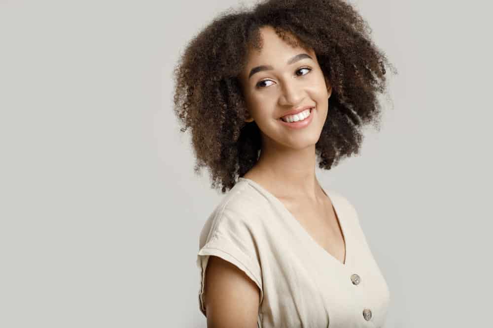 A cute young black girl with bouncy curls and full fringe bangs styled with volumizing product.