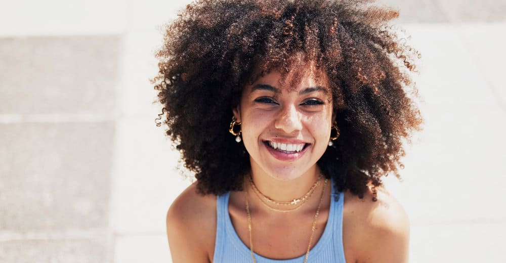 A black girl with a great smile used a deep conditioner and affordable protein treatment to repair hair damage.