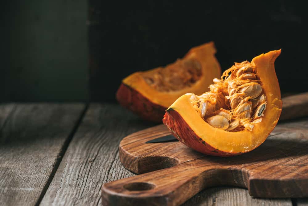 A pile of raw, unshelled pumpkin seeds still attached to the pumpkin.