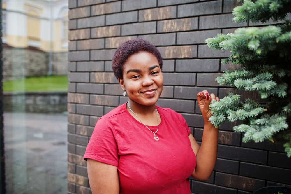 A black female with a 4C kinky hair texture wearing very short hair that highlights natural curls and coily hair strands.