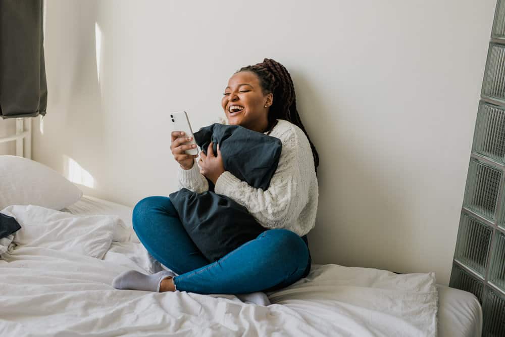 African American female with a round face has a short hair length is researching round chubby faces on her iPhone.