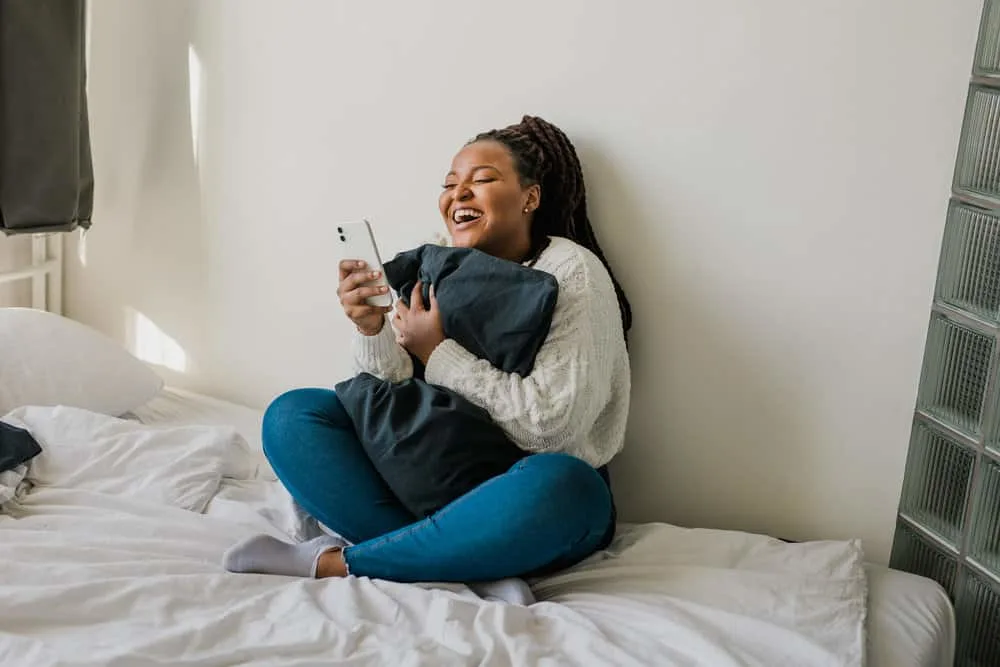Best Haircuts for Fat Faces and Round, Chubby Double Chins 16 African American female with a round face has a short hair length is researching round chubby faces on her iPhone.