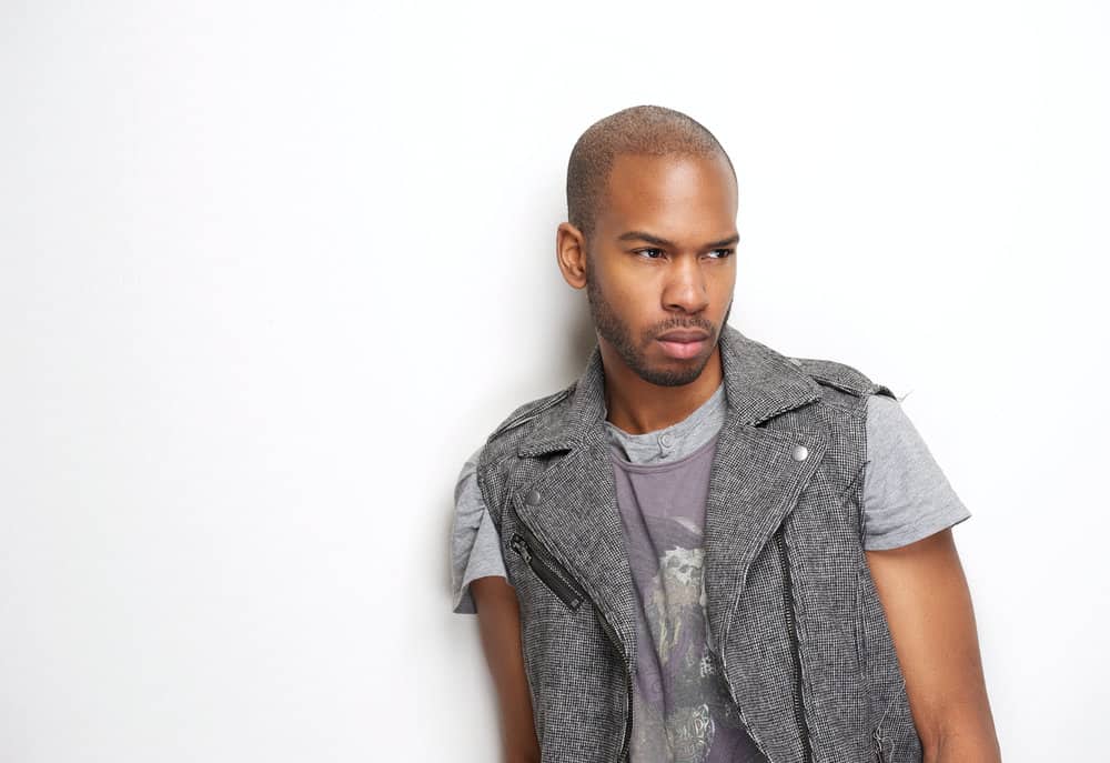 A sophisticated African American man with a drop fade, a military-inspired haircut is wearing casual clothes.