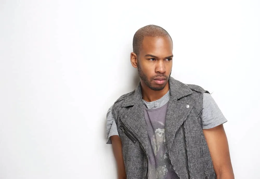 Best Male Haircuts for Receding Hairline and Widow’s Peak 7 A sophisticated African American man with a drop fade, a military-inspired haircut is wearing casual clothes.