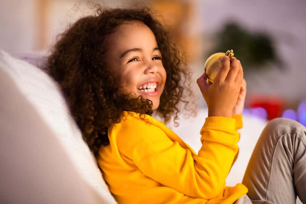 A delightful little girl with curly fine hair styled with a mist of coconut oil and water in a spray bottle to create volume.