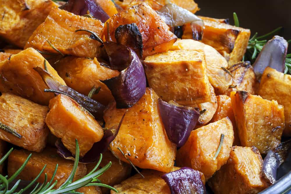Baked sweet potatoes, showcasing their rough and uneven skin in varying shades of orange and brown.