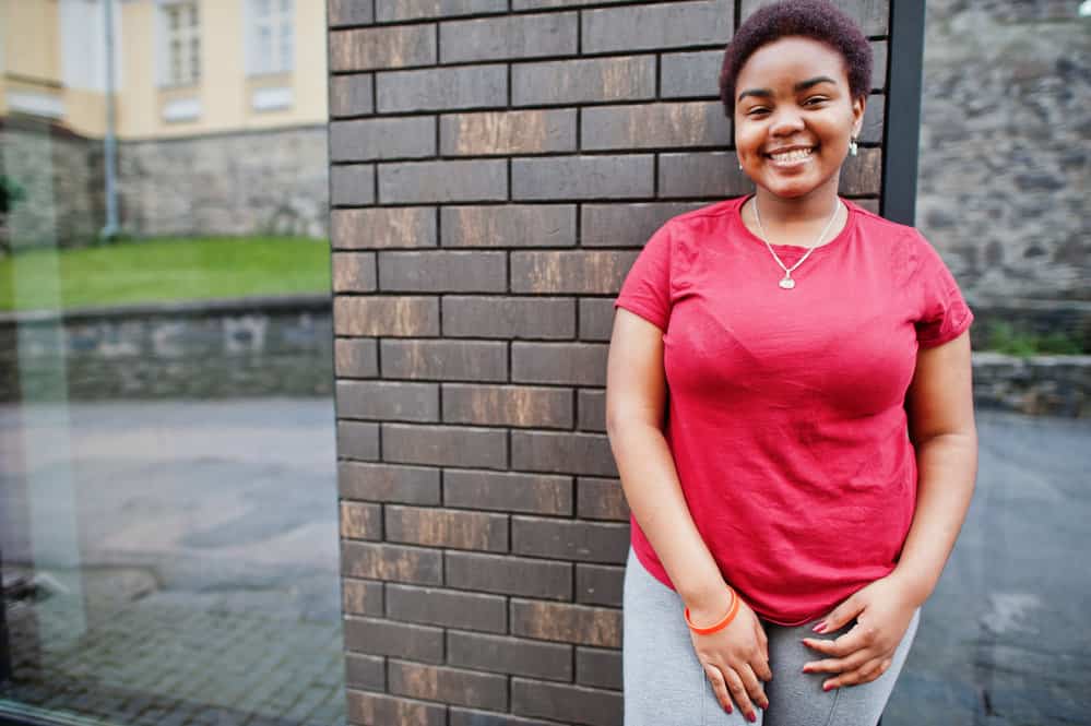 A lady wearing a red t-shirt with jogging pants with a stylish short afro that was dyed with Manic Panic purple haze.