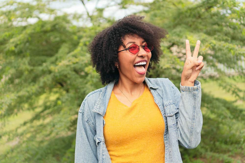 An African American female with healthy hair follicles styled with natural oils like coconut oil and castor oil.