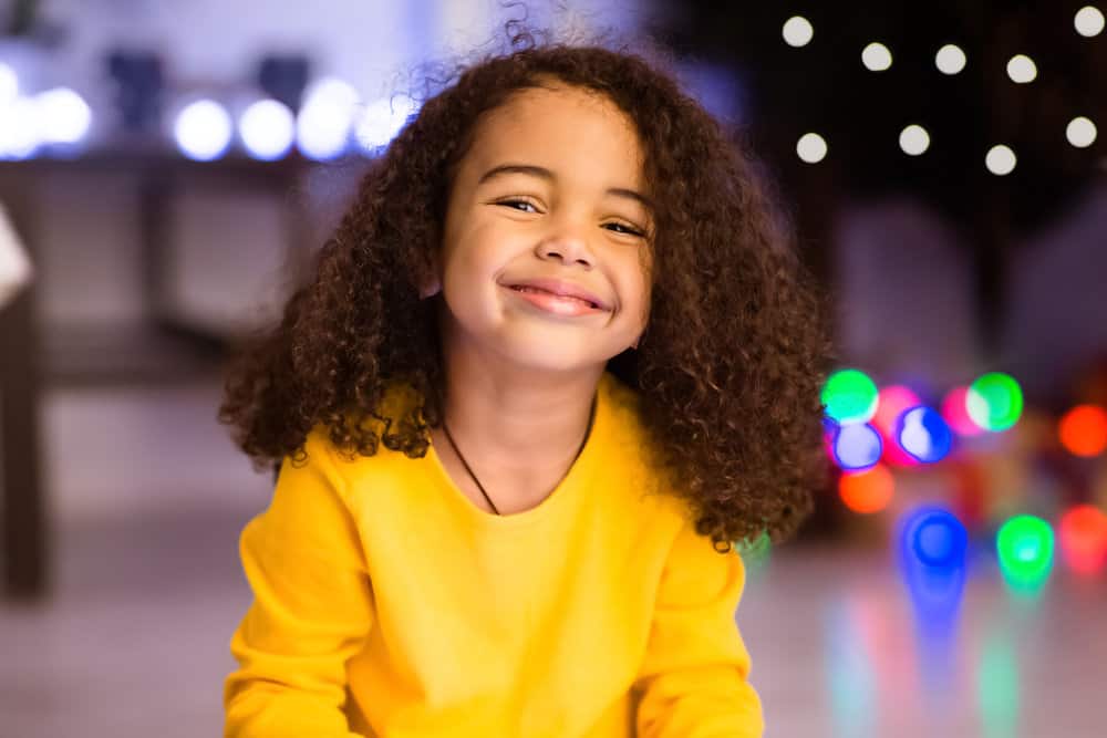 A cute toddler girl's hair is worn in a loose shoulder-length hairstyle after removing a curly fishtail braid.