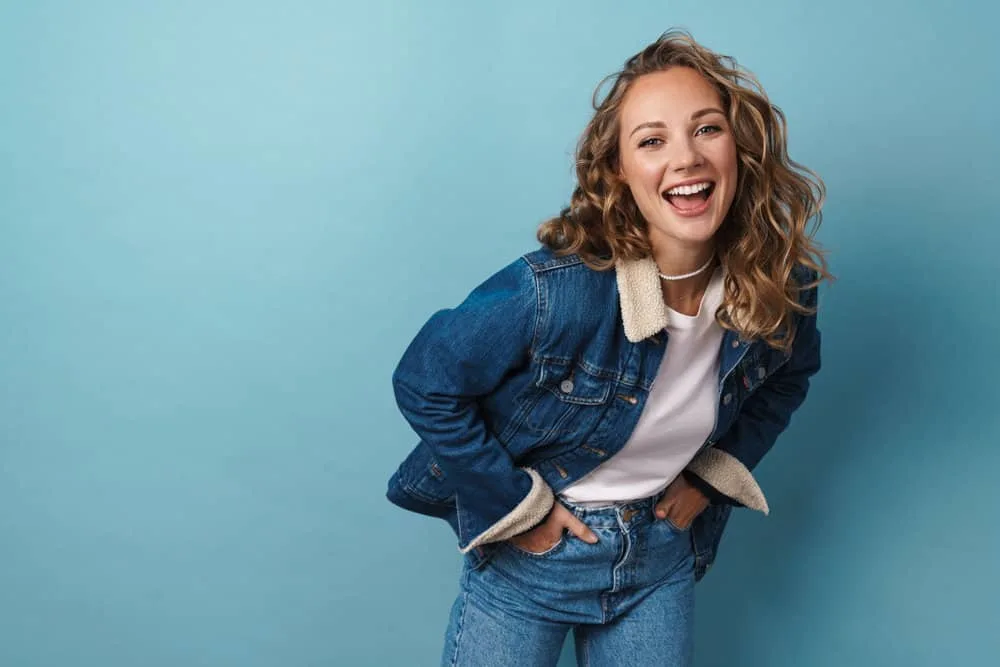 How to Get Butterscotch Hair Color and What Does It Look Like 8 A stylish young white woman wearing a curly auburn brown butterscotch hairdo with ash blonde undertones.