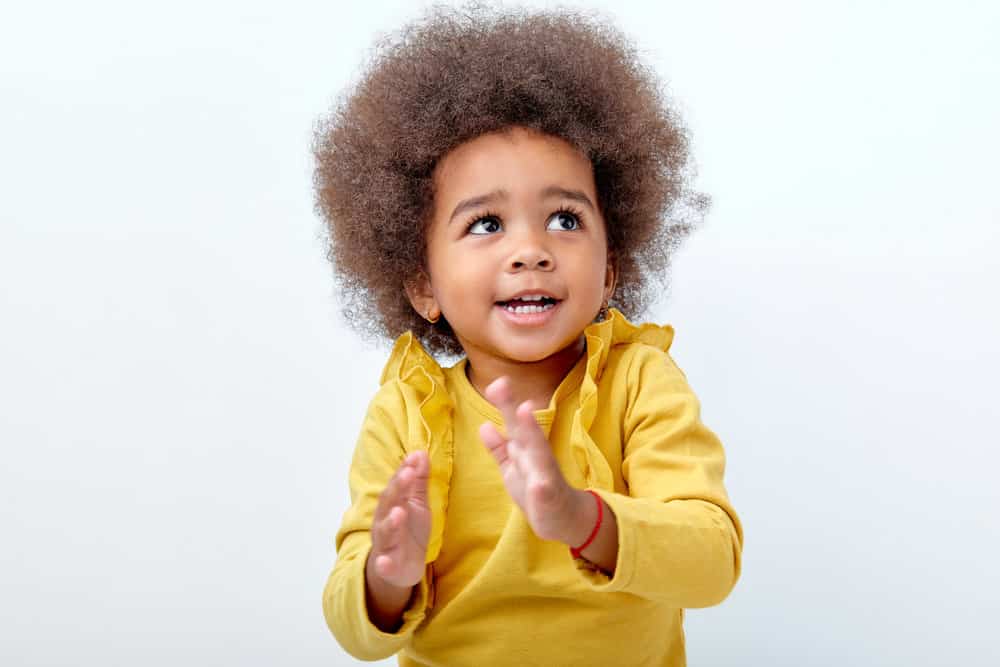 A charming black baby with a type 3 natural hair type, wearing a colorful bow in her naturally kinky hair.