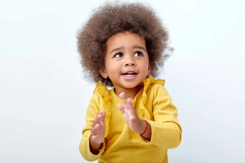 7 Cute & Easy Infant Black Baby Girl Hairstyles with Tutorials 11 A charming black baby with a type 3 natural hair type, wearing a colorful bow in her naturally kinky hair.