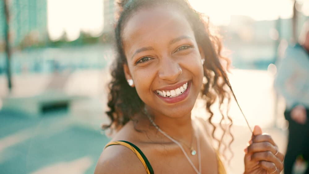 A black woman with long curly hair uses a rice water rinse within her hair regimen to promote hair growth.