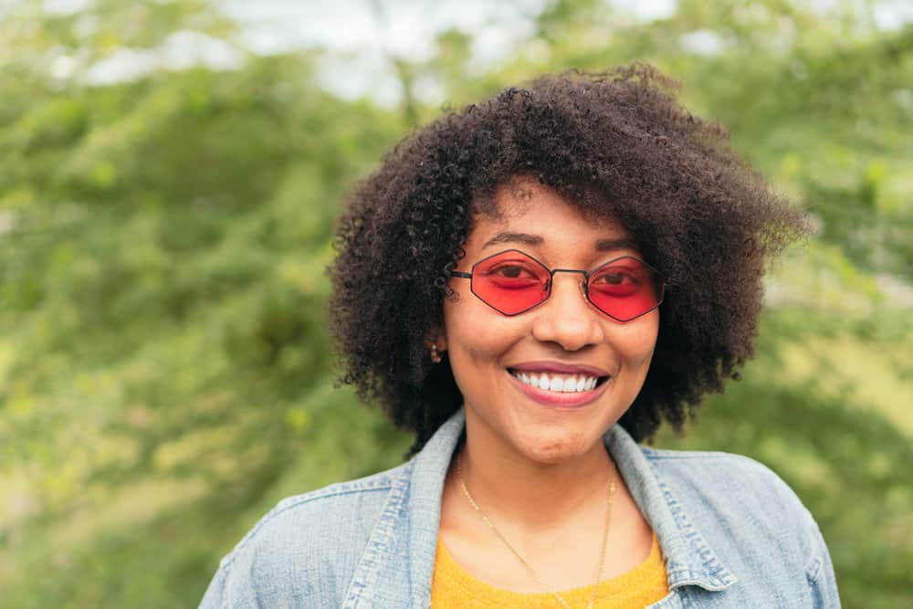 A black girl with oily skin and frizzy hair used an Aztec clay hair mask to restore damage to her type 4 curl pattern.