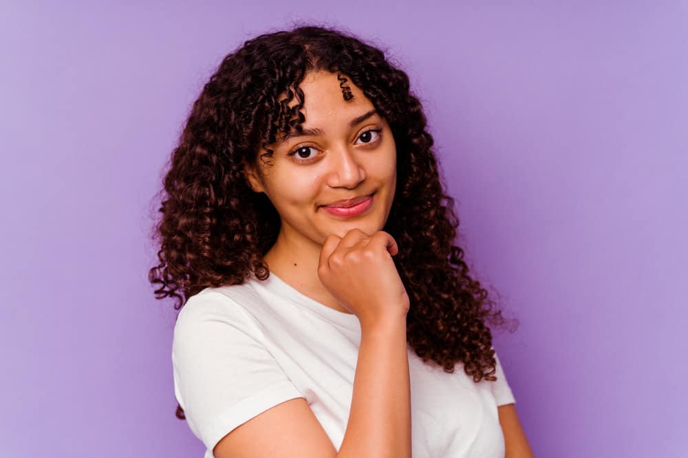 A stunning African American female wearing a white shirt, cute red lipstick and a gorgeous curly hairstyle.