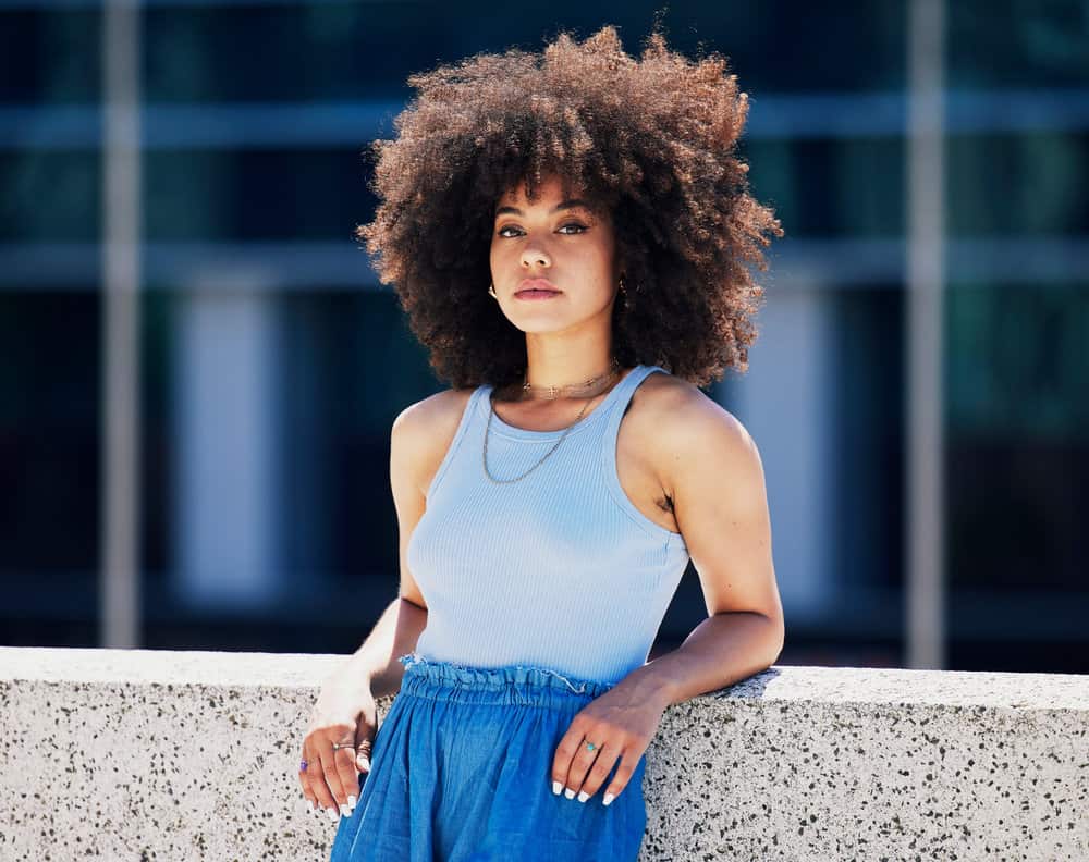 A black woman in the city with type 4 curls styled with coconut oil and Jamaican black castor oil, making her hair soft.