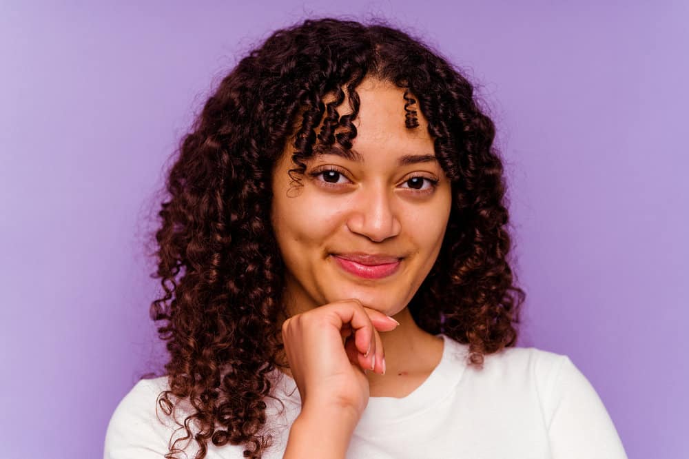 A beautiful African woman with curly hair showing olive oil before and after photo from treating hair loss.