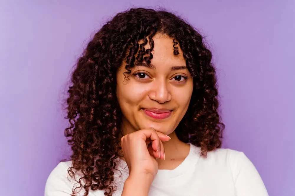 A beautiful African woman with curly hair showing olive oil before and after photo from treating hair loss.