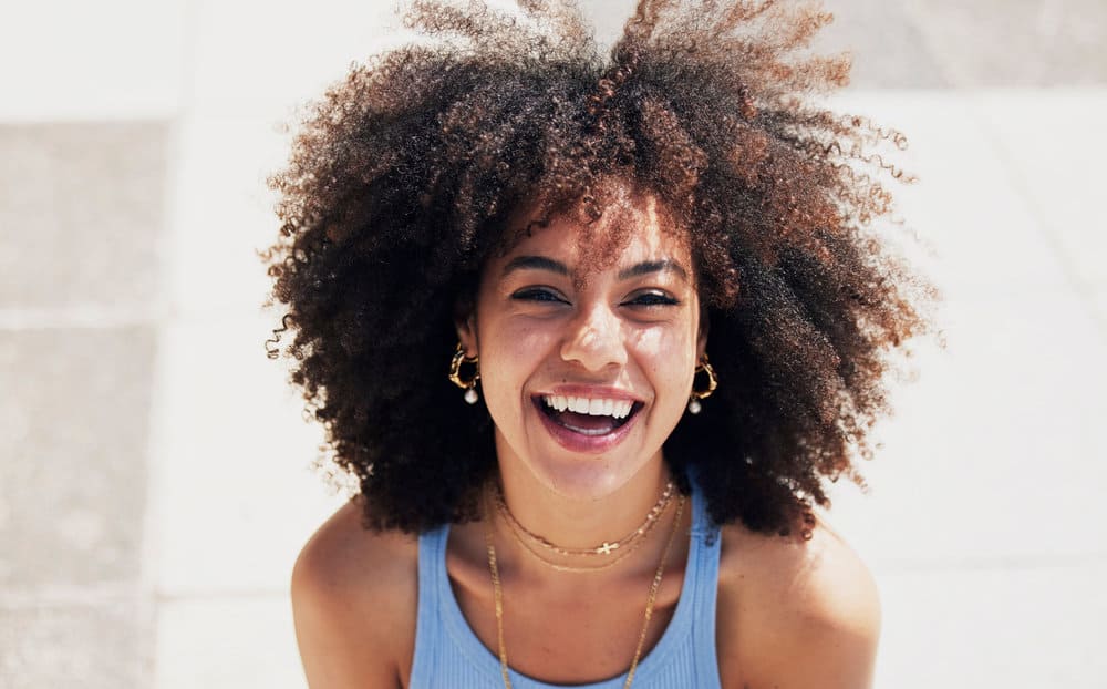 A beautiful black woman with dry and brittle hair after using too much protein on her naturally wavy hair.